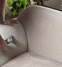 Professional upholstery cleaner deep-cleaning a fabric sofa with a handheld extraction tool and hose Charlotte, NC.